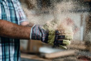 Hands clapping together releasing visible dust particles into the air — representing workplace dust exposure and air quality monitoring.