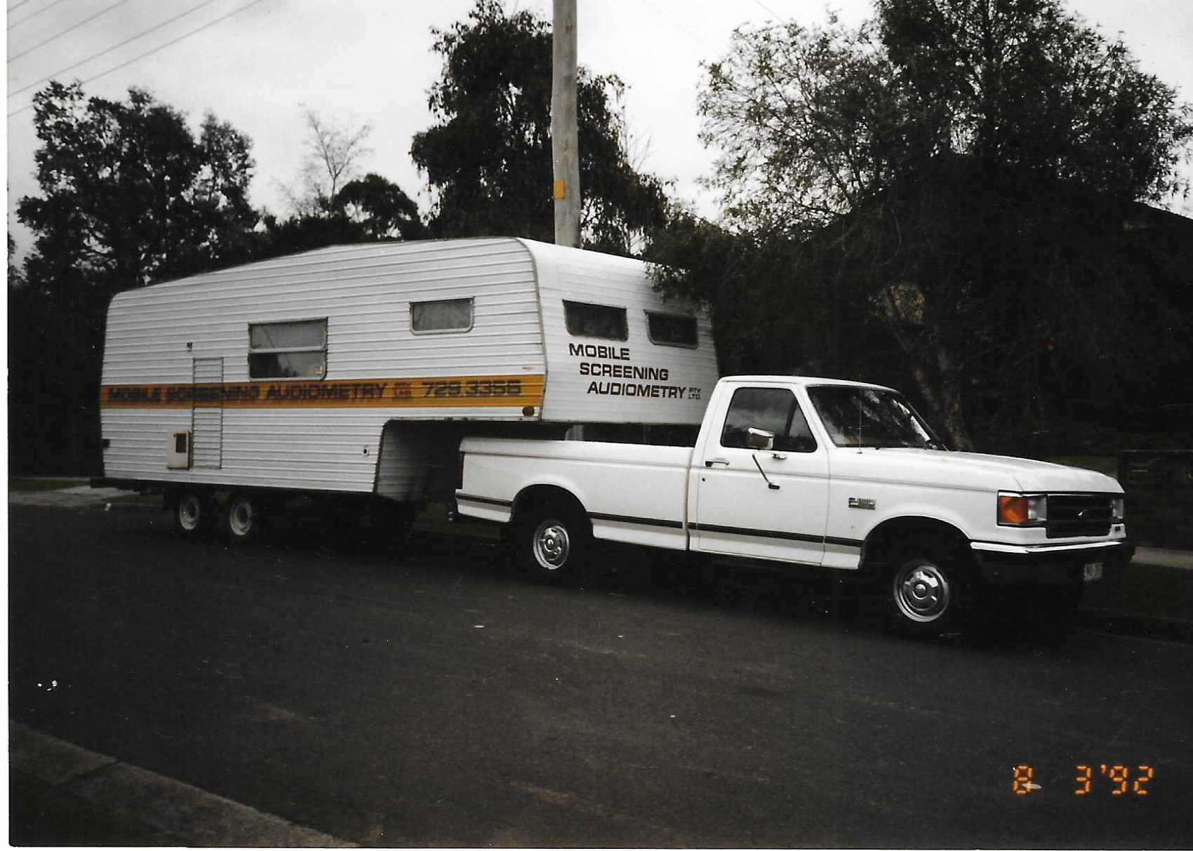 1992 Ford F150 ute towing Mobile Screening’s audiometric screening trailer, reflecting the company’s growth in workplace hearing tests and noise assessments under Chris Webb’s ownership.