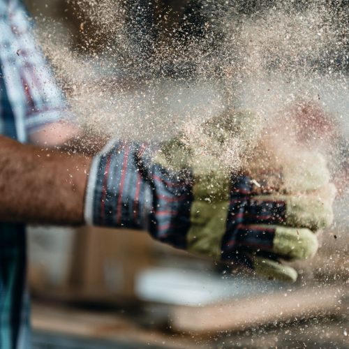 Hands clapping together releasing visible dust particles into the air — representing workplace dust exposure and air quality monitoring.